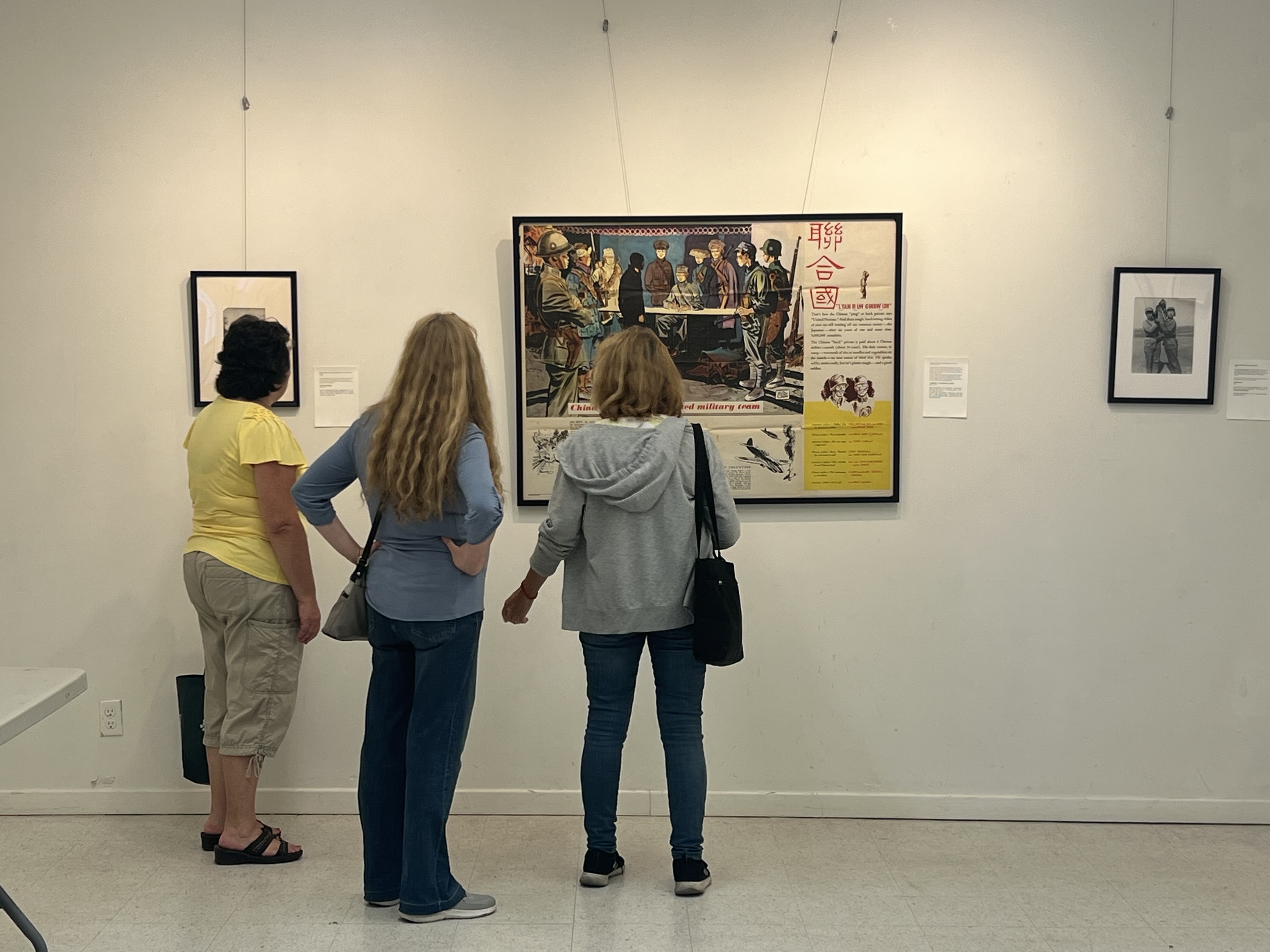Visitors reading exhibition materials in front of an Allied wartime poster.
