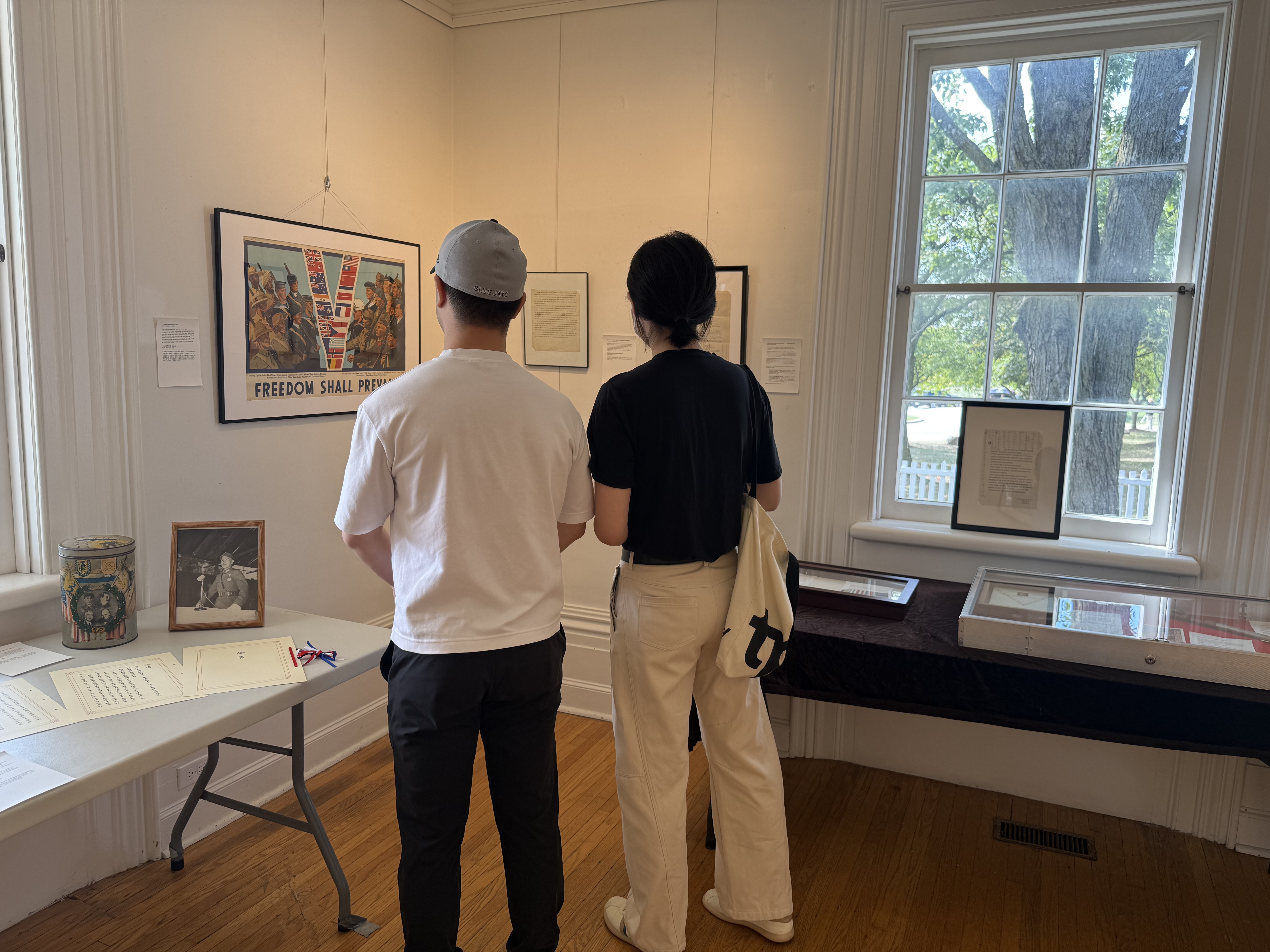 Visitors viewing MOFER exhibition materials between tall windows at Boynton House.